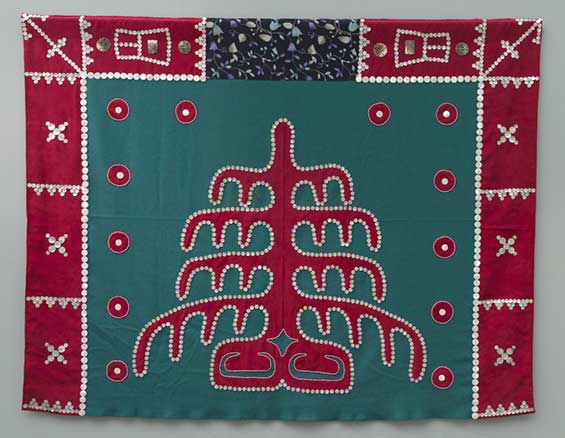 Button blanket with red frame on top and sides, green centers square with tree of life pattern and decoration.
