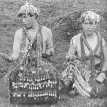 Photographie noir et blanc montrant deux jeunes hommes en attirail d'écorce de cèdre, collier, chapeau tressé et tablier de danse.