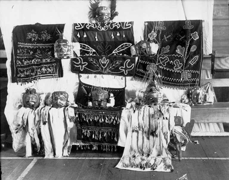 Sur un fond blanc sont exhibés quatre tabliers de danse, des masques et des coiffes, certaines ont une trainée d'hermine.