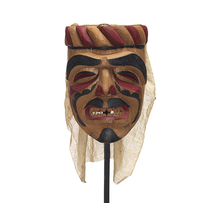 Un masque d'ancêtre Imas à coiffe sculptée, peinture faciale dramatique en noir et rouge, expression grimaçante, voile en coton.