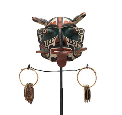 Xwixwi mask representing red snapper or cod, shown with sea shell rattles. Large protruding eyes, drooping tongue, 4 animal figures project from temples and cheeks.