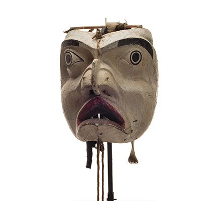 Forest spirit mask, mostly white face, deeply carved features, black paint eyebrows and around eyes, cloth and leather strips attached to back