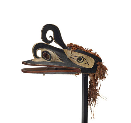 A supernatural man-eating bird, with raven like features, elaborate carved detail, mostly black with white and red markings and cedar trim.