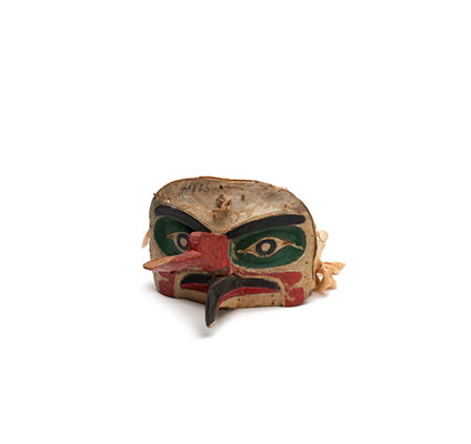 A 'Na'nalalał or weather mask, long red proboscis over a curved beak painted black with red edges, green patches around eyes, cloth head band.