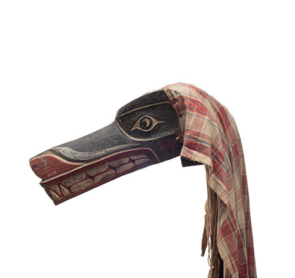 Un des masques de loup Xisiwe’ peint en rouge et noir, au long museau, dentu, des restes un voile de coton uni.