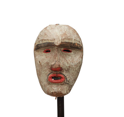 Un masque blanc, du rouge autour des yeux plissés percés, des narines et des lèvres, fine moustache et sourcils épais.