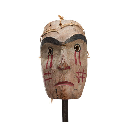 Kwasanuma or mourning mask, cedar with red drips of paint below eyes, cross-hatch pattern in red on cheeks, mournful expression.
