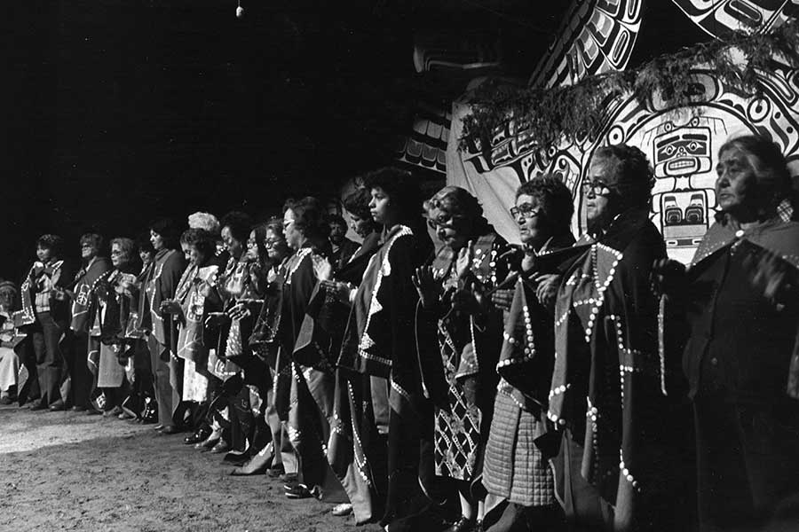 Photographie noir et blanc un chant lors de la cérémonie de deuil, au potlatch d'Owaxalagalis, chef Roy Cranmer, en 1980.