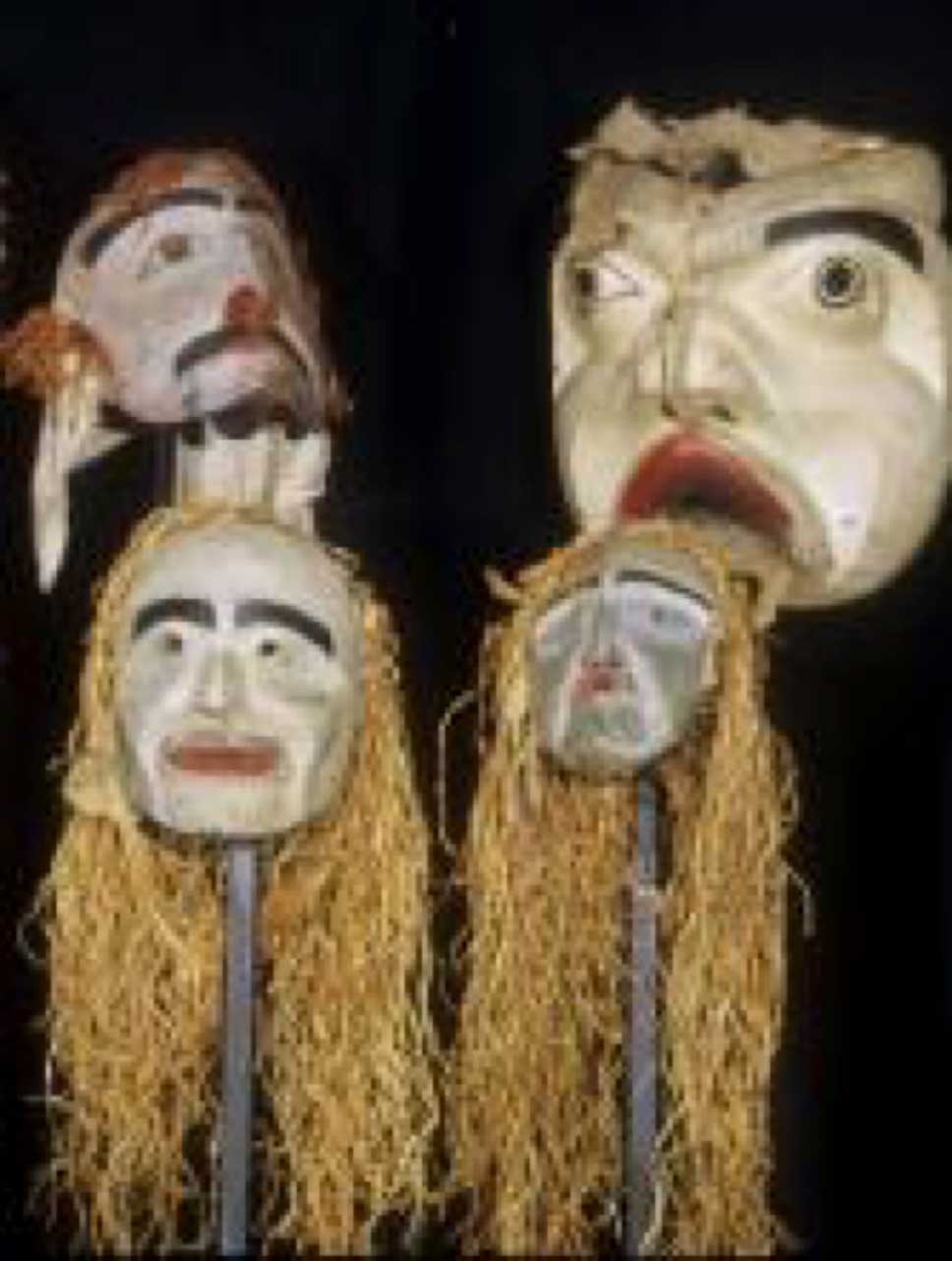Photographie couleur montrant un groupe de quatre masques d'esprits sylvestres, prise sur un fond noir