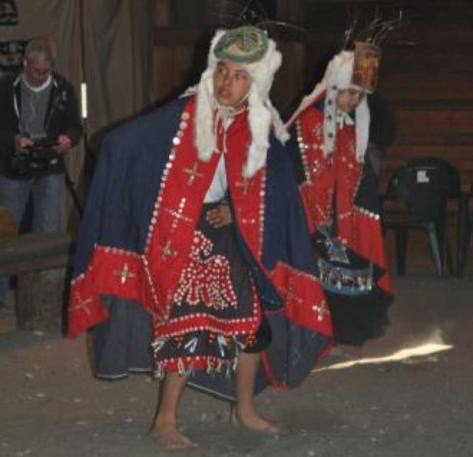 Two young dancers barefoot wearing dance aprons and button blankets, ermine headdress with carved frontlet headdress