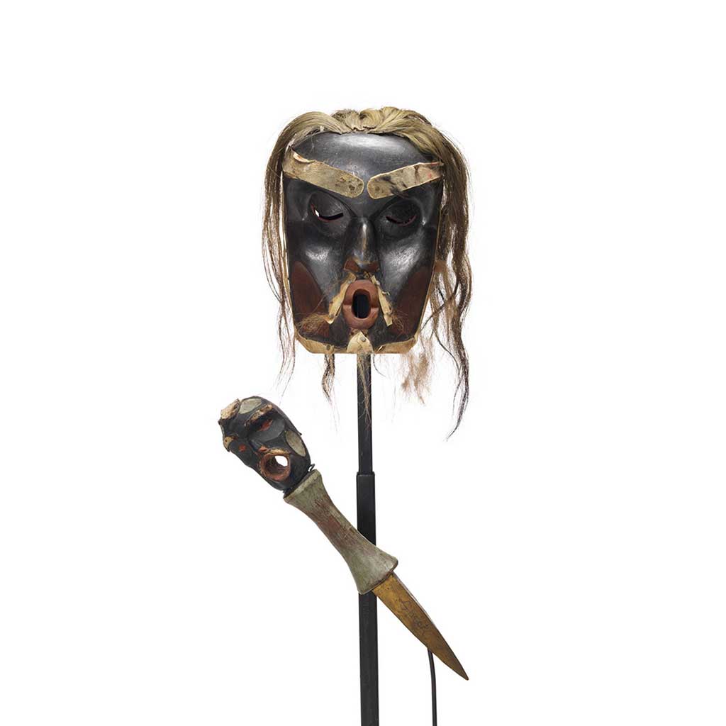 A Chief's Dzunuḱwa mask and copper breaker, mask is deeply carved, dark with red patches, light hair trim.