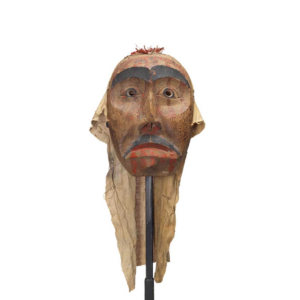 A mourning mask red cedar with painted black eyebrows pupils and moustache. Red paint drips on the forehead, below eyes and lips.