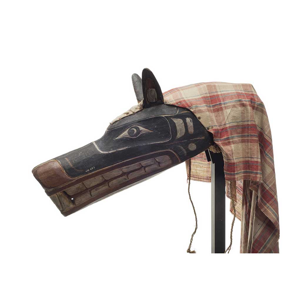 Xisiwe’ or wolf mask, one of several with long snout and large teeth, painted red and black with plaid cotton head cover, prominent upright ears.
