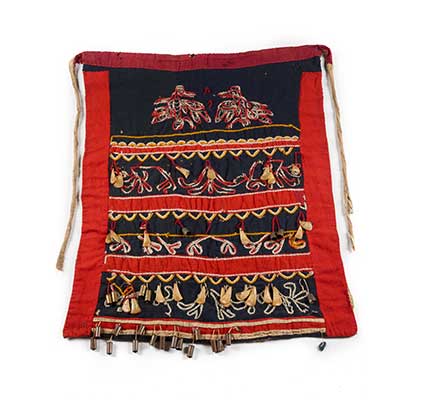 Tsep or dance apron, black background with red trim, embroidered ravens and abstract floral designs with puffin beaks, thimbles and bullet casings.