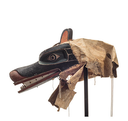 Un masque d'ours Nan à longue gueule noire articulée et dentue, lèvres et museau peints en rouge, voile en cuir.