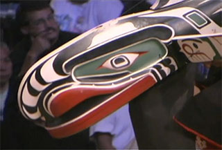 The front part of a brightly painted whale mask appears to dive in a downward diagonal from right to left.