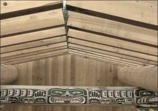 Image montrant une section du toit de la maison cérémonielle d’Alert Bay fait de poutres en cèdre et d’une poutre traverse sculptée et peinte en forme de Sisiyutl.
